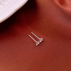 Close-up of minimalist silver stud earrings with sparkling cubic zirconia on brown fabric