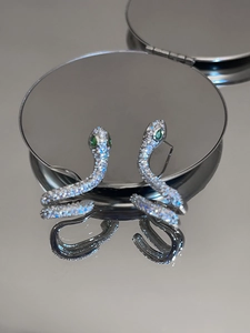 Gros plan de boucles d'oreilles serpent argentées avec zircon pavé et yeux en pierres vertes