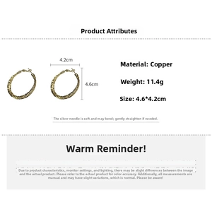 Detail view of large golden textured hoop earrings with silver needles and hammered finish