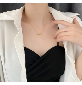 Detail of a minimalist gold hollow heart necklace worn on a neck for a modern look