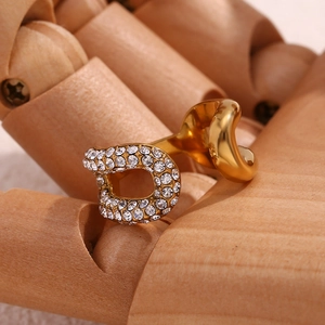 Dettaglio macro dell'anello a catena placcato oro 18K con micro cristalli su mano in legno
