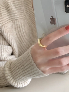 Minimalist square golden geometric ring worn on finger with a knit sweater backdrop