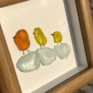Art d'oiseaux en verre de mer dans un cadre en bois avec des oiseaux colorés en galets