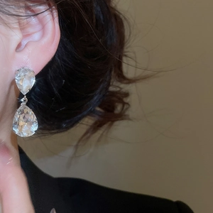 Close-up of elegant silver teardrop crystal earrings with flowing tassel design on model