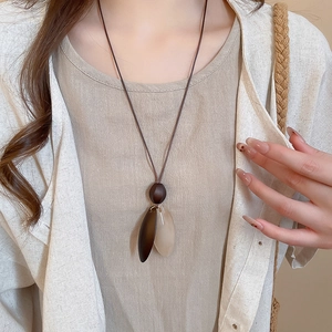 Detail of a vintage resin pendant on a brown cord over a cream linen shirt