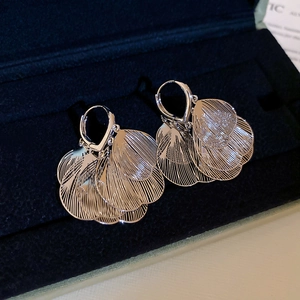 Détails de boucles d'oreilles fleuries en filigrane d'argent sur velours bleu