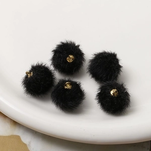 Detailed view of five black faux fur pom-pom pendants with gold hanging loops for DIY jewelry