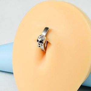 Macro shot of silver skull belly button ring with white rhinestones on silicone model