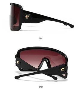 Detail view of oversized black sunglasses with gradient red lenses and gold C-logo on temple