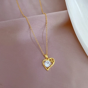 Elegant gold heart pendant necklace with a sparkling white zircon on soft fabric backdrop
