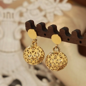 British vintage hollow ball earrings in gold finish with zircon inlay on a wood stand
