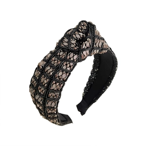 Luxury knotted black headband with golden metallic weave texture on a white background