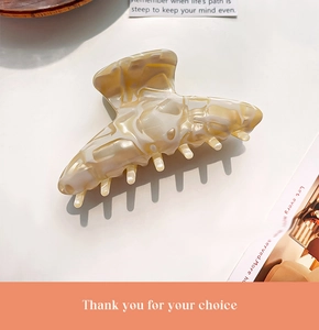 Detailed close-up of cream marble texture acetate hair claw clip on white background