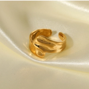 Detailed close-up of a gold irregular lava ring on premium beige satin fabric background