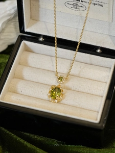 Macro detail of 18K gold-plated necklace featuring an oval emerald green zircon pendant
