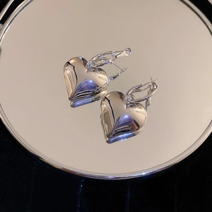 Polished silver heart earrings on reflective mirror surface with dark velvet background