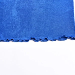 Detail of blue knit fabric showing the wavy ruffled hem and textured stitching design