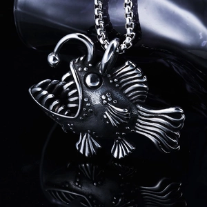 Macro detail of vintage anglerfish pendant with sharp teeth on a silver box chain