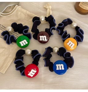 Détails de cinq chouchous en tissu coloré avec perles factices et lettres M en résine