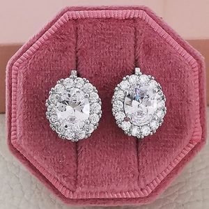 Macro shot of silver halo earrings with oval zircon stones in a pink velvet jewelry box