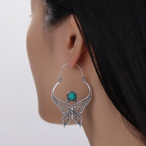 Bohemian silver hollow butterfly earrings with turquoise bead inlay on female model