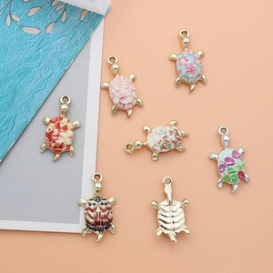 Detailed flat lay of seven colorful turtle-shaped alloy pendants on a pink backdrop