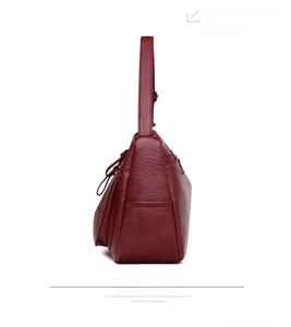 Detail of dark red crossbody bag with lychee texture and side zipper pocket