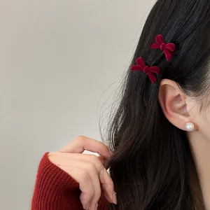 Pair of red velvet bow hair clips on black wavy hair with soft lighting