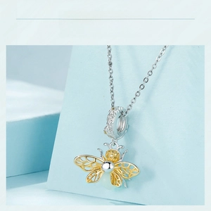 Detail of s925 silver bee pendant with gold wings and yellow gems on blue stand