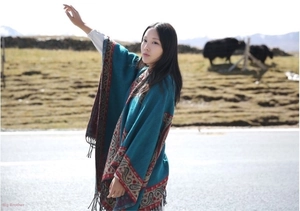 Ethnic peacock blue shawl with paisley patterns and tassels on a scenic road