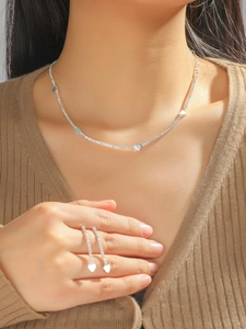 Close-up of sparkling silver rhinestone heart necklace and long fringe earrings on model