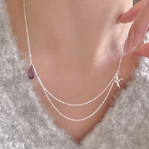 Close-up of double layer silver necklace with purple teardrop bead and swallow pendant