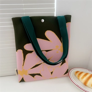 Detail of green knitted floral tote bag with pink flower pattern and silver magnetic closure