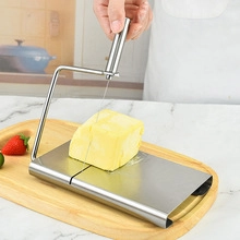 Close-up of hand using a stainless steel butter slicer on a wooden board in a kitchen