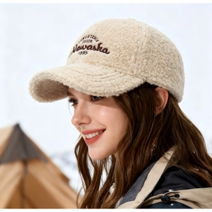 Gros plan sur une casquette beige en laine d'agneau avec broderie en décor enneigé
