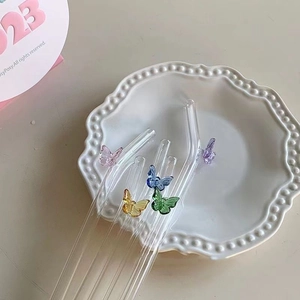Transparent butterfly glass straws with curved and straight tips in a ceramic tray