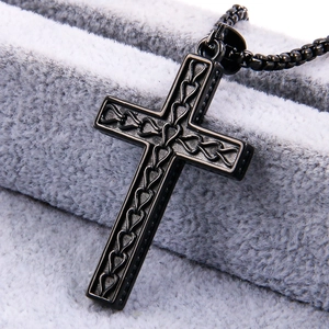 Close-up of textured black stainless steel cross pendant in a gray velvet jewelry box