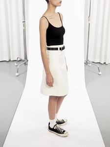 Detail view of cream A-line midi skirt with black camisole top and leather belt set