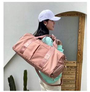 Action shot of a pink large travel bag worn crossbody by a model in outdoor setting