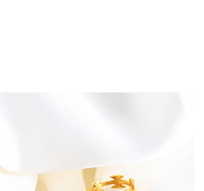 Detail of a matte gold ring featuring a modern hollow criss-cross geometric design