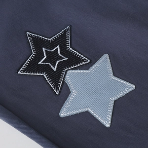 Detail of star patches embroidered with white stitching on navy blue knitted fabric