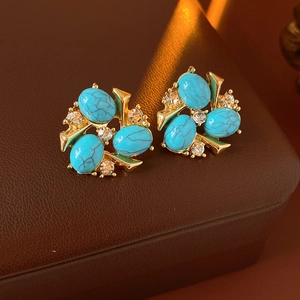Gros plan de boucles d'oreilles vintage dorées avec turquoises et strass brillants