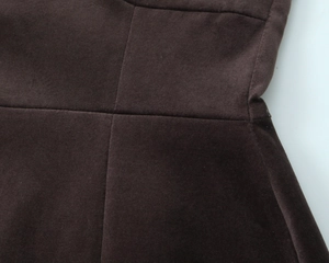 Gros plan du tissu en velours marron avec coutures en croix sur la robe courte