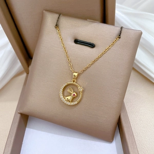 Detailed close-up of a gold rabbit pendant with red eye and crystals in a velvet box