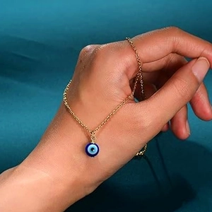 Detail view of a golden stainless steel chain with a blue evil eye lucky charm pendant