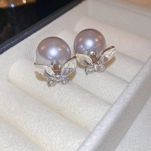 Macro view of butterfly earrings with purple pearls and zircons in a jewelry box