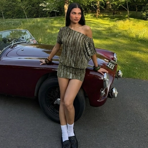 Detail of green and brown tie-dye mini dress on model leaning against a vintage car