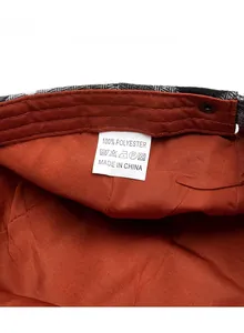 Detail view of orange polyester lining and care label inside the checkered beret cap