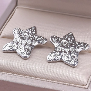 Close-up of star-shaped silver earrings with hammered texture in jewelry box