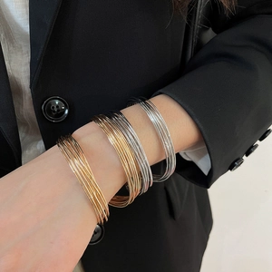 Detail shot of multi-layer metallic wire bracelets in gold, silver, and black finishes